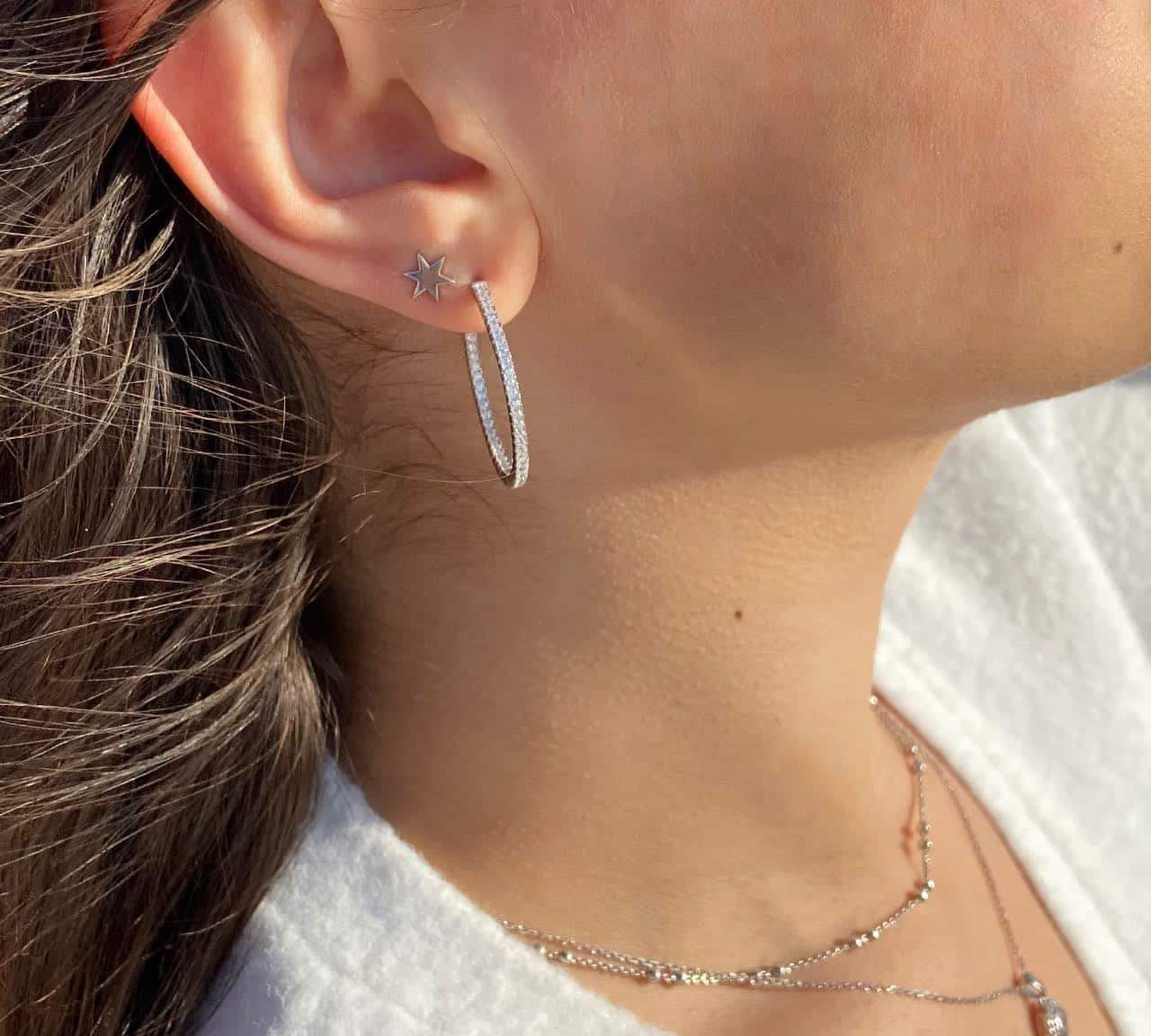 Boucles d'oreilles créoles et puce étoile en argent rhodié avec zircons sur une oreille