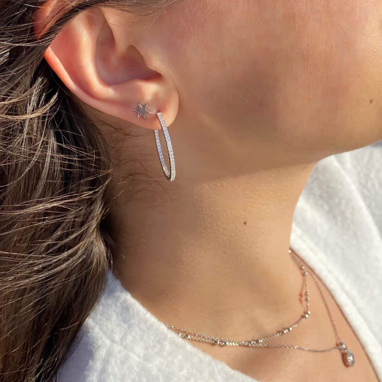 Boucles d'oreilles créoles et puce étoile en argent rhodié avec zircons sur une oreille