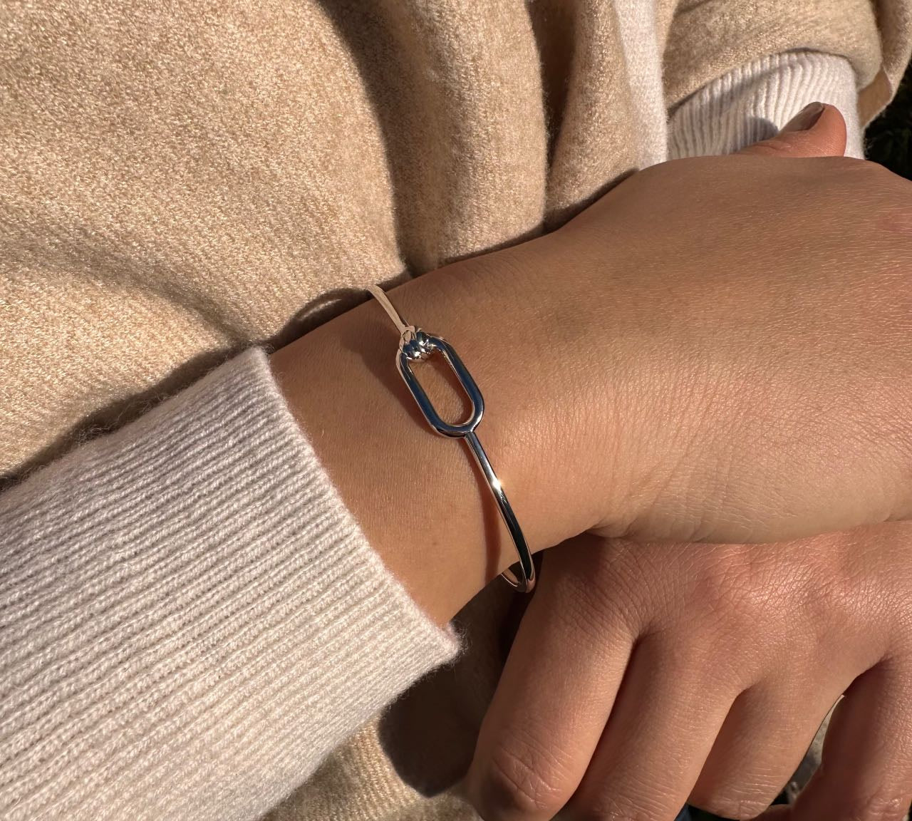 Bracelet jonc argenté élégant porté au poignet, bijou chic et minimaliste pour femme