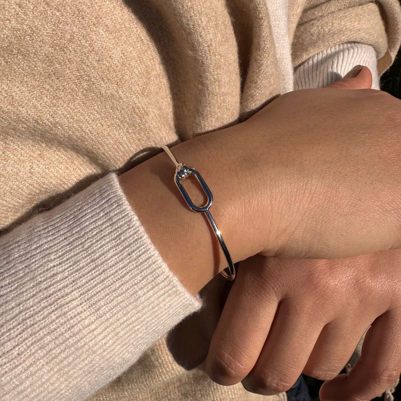 Bracelet jonc argenté élégant porté au poignet, bijou chic et minimaliste pour femme