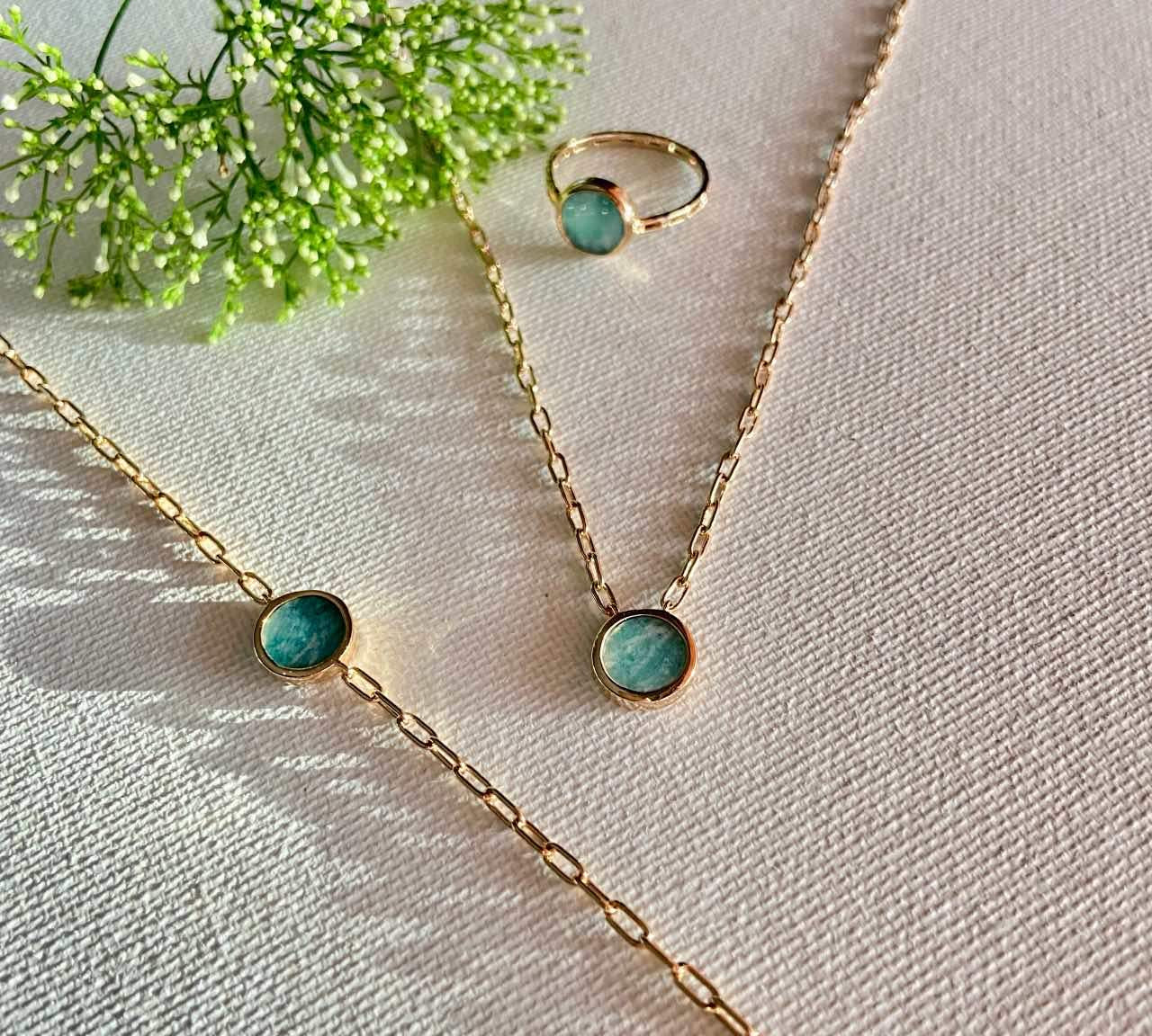 Collier et bague en or avec pierre bleue verte sur fond clair, bijoux chics pour femme