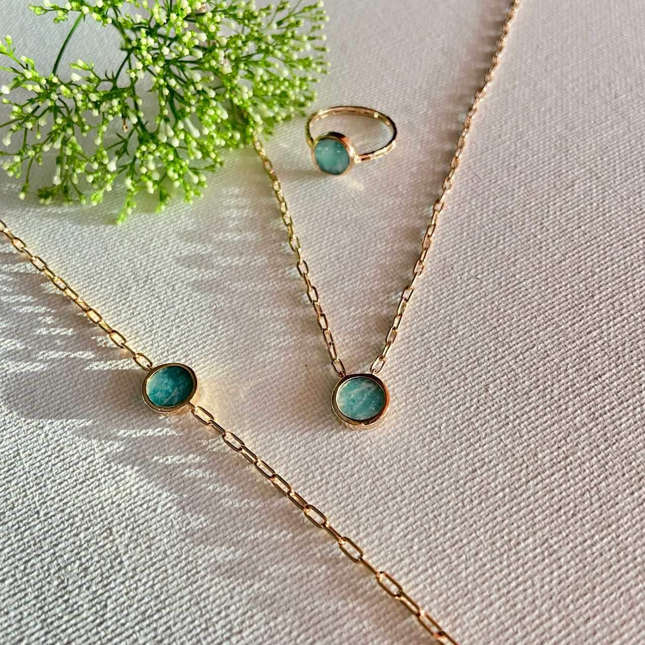 Collier et bague en or avec pierre bleue verte sur fond clair, bijoux chics pour femme