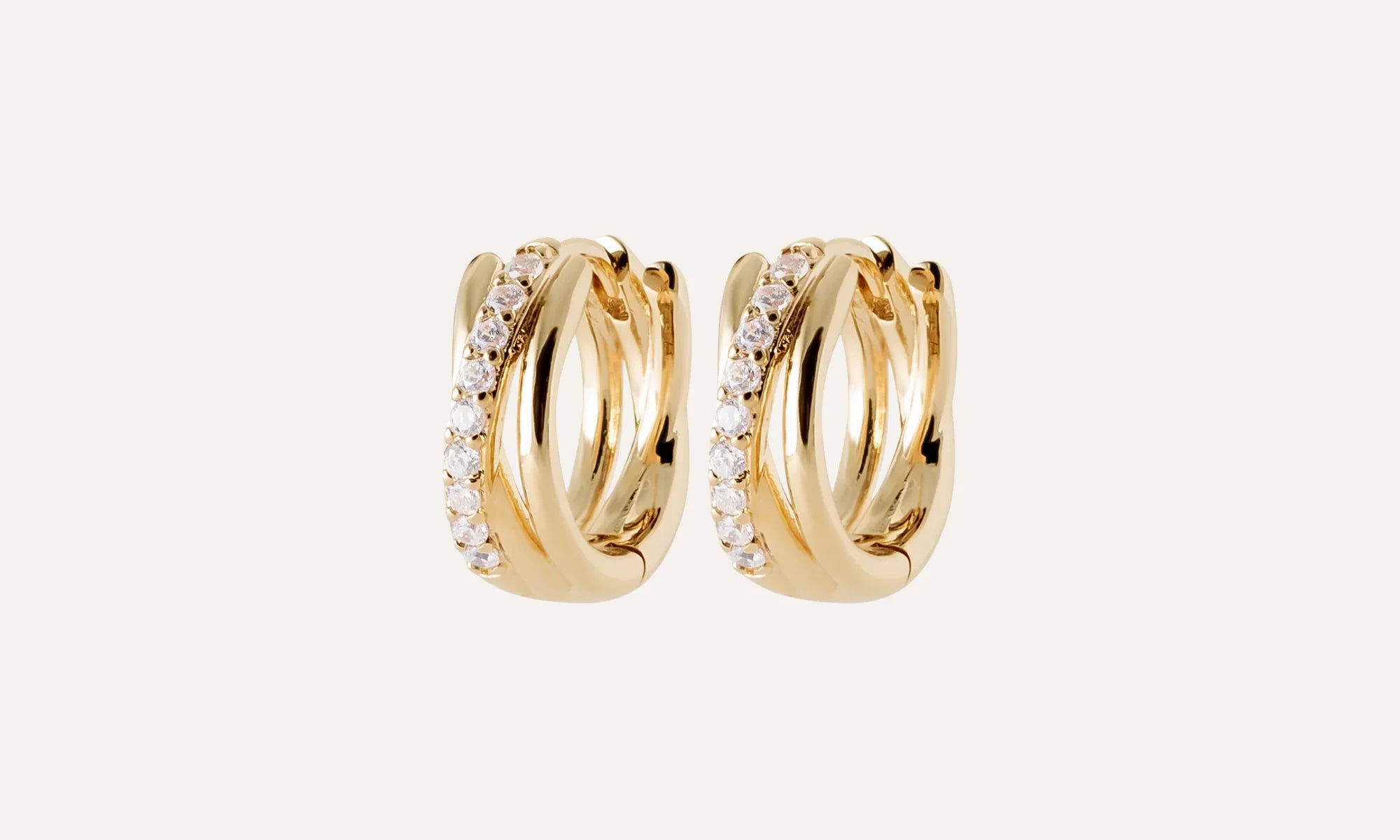 Boucles d’oreilles créoles dorées serties de pierres, bijou chic sur fond clair