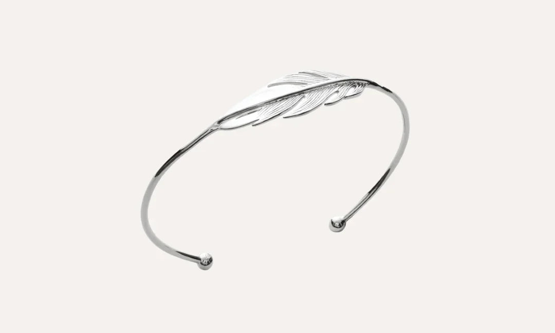 Bracelet jonc argent ouvert avec motif plume élégant sur fond uni, bijou chic femme