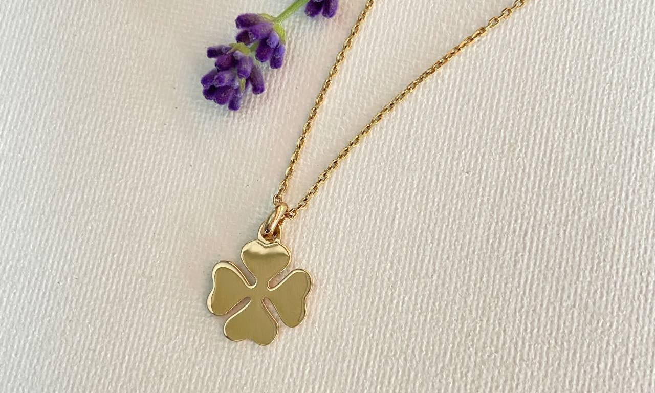 Collier chic trèfle doré sur fond clair avec fleur violette pour femme élégante