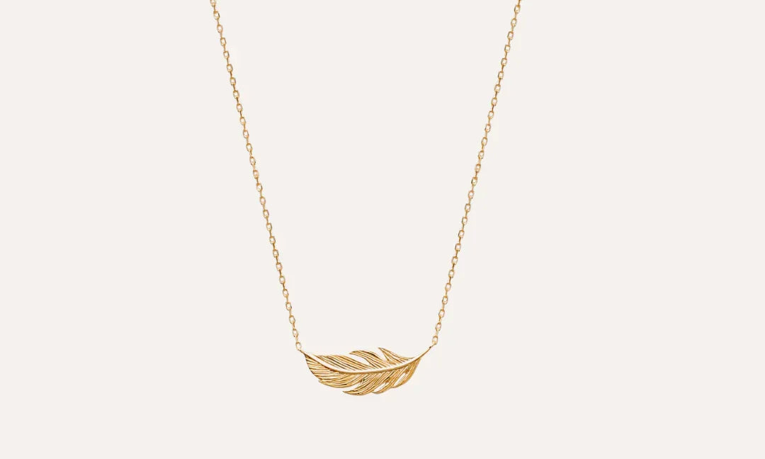 Collier chic en plaqué or avec pendentif plume sur fond clair, bijou élégant
