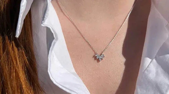 Collier élégant en argent avec pendentif papillon, porté sur chemisier blanc, bijou chic.