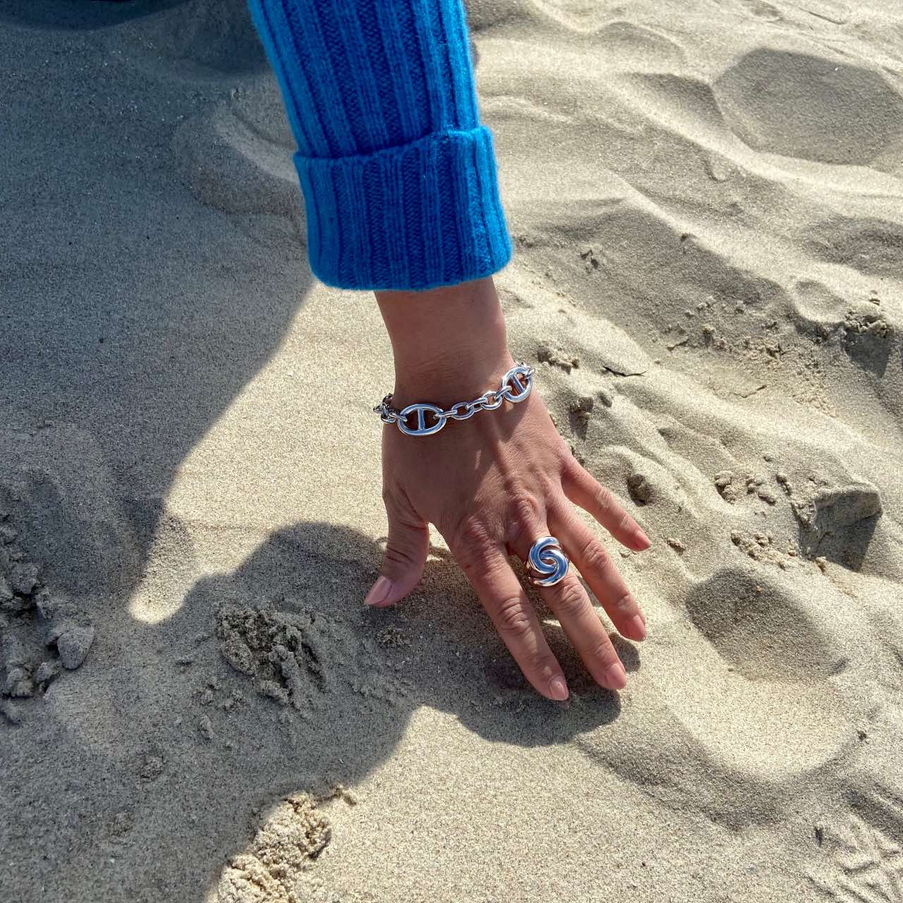 Gros bracelet argent rhodié porté sur fond de sable