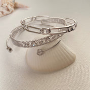 3 bracelet jonc en argent rhodié sur un coquillage
