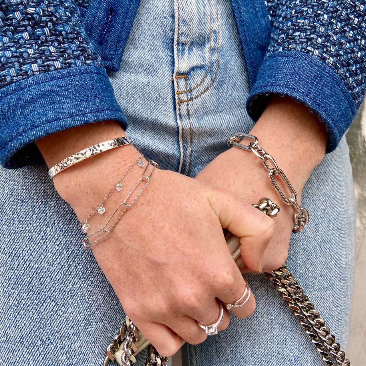 Bracelets argentés tendance portés sur jean et veste, accessoires mode élégants