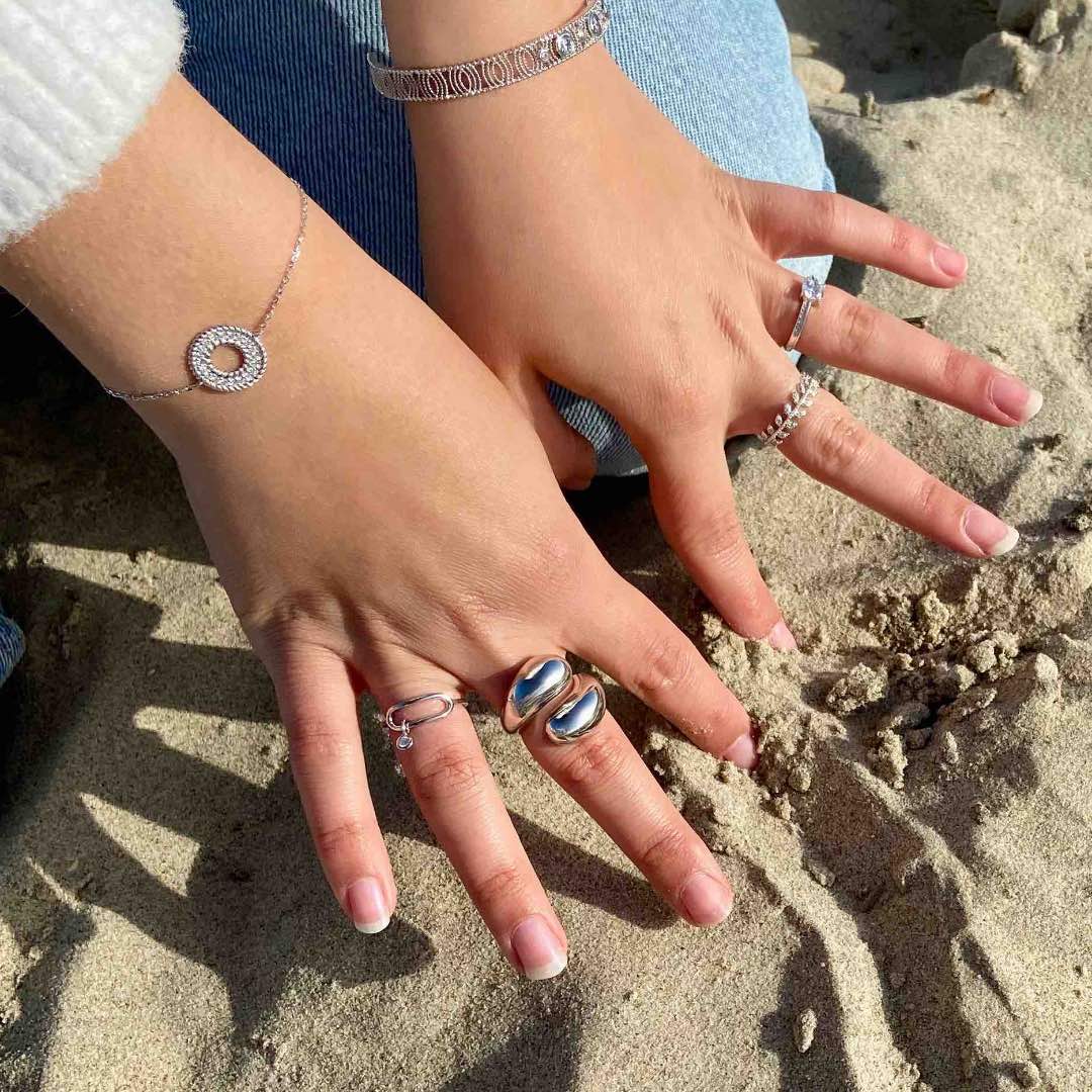 jeune fille portant des bagues en argent fond sable