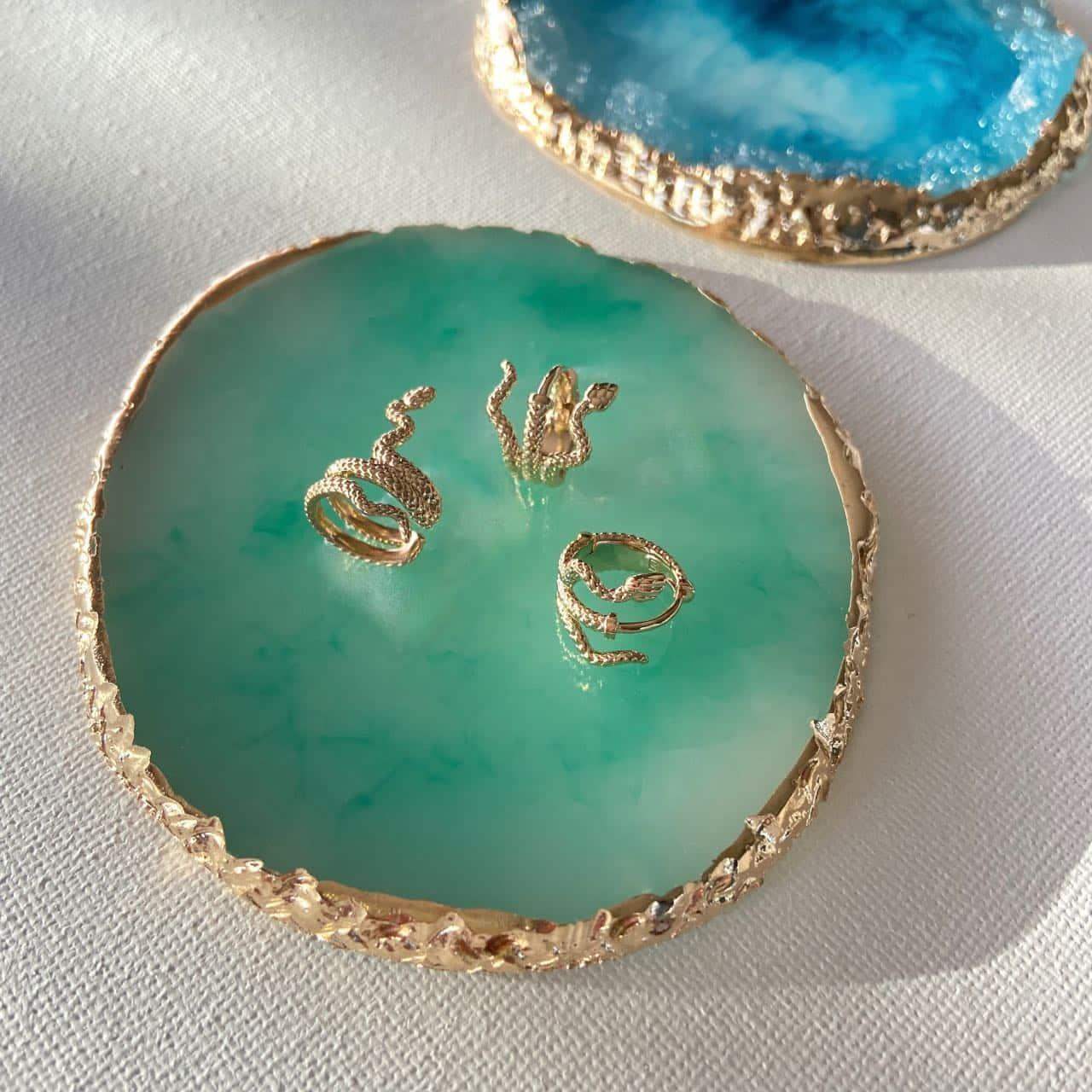 Trois bagues d'oreille serpent plaqué or Siryna de les bijoux chics sur un plateau en agate verte.