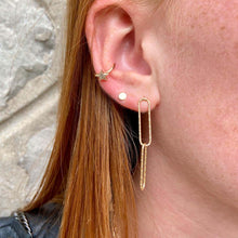 gros plan sur une boucle d'oreille puce lisse et plate en plaqué or accompagné d'une bague d'oreille étoile
