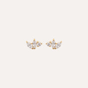 Boucles d’oreilles puces dorées avec trois zircons, style chic et élégant, fond clair.