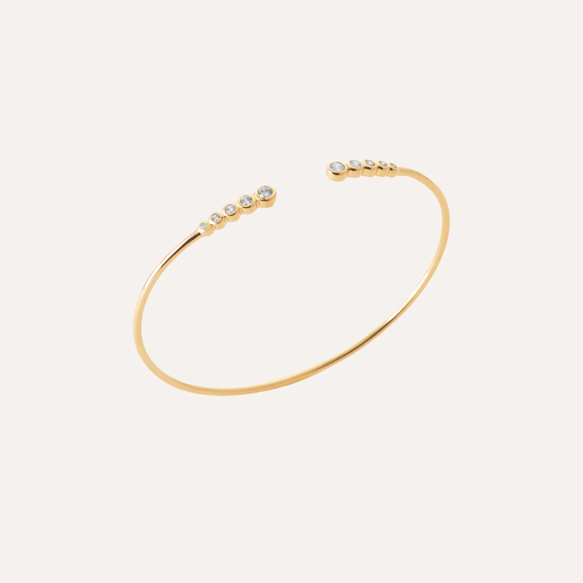 Bracelet jonc plaqué or fin avec rangée de petites pierres sur le dessus.