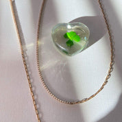 Collier asymétrique en plaqué or, gros plan sur la fusion d'une chaîne à maillons rectangulaires et d'un rang d'oxydes de zirconium.