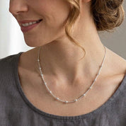 Collier chaine argent boules porté par une femme blonde avec un chemiier gris
