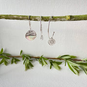 Créoles en argent sur fond végétal