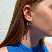 gros plan sur une bague d'oreille en argent avec 3 oxydes de zirconium