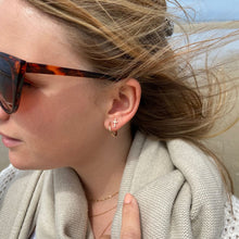 Créoles dines 16 mm et boucles d'oreilles croix portées par une jeune femme blonde