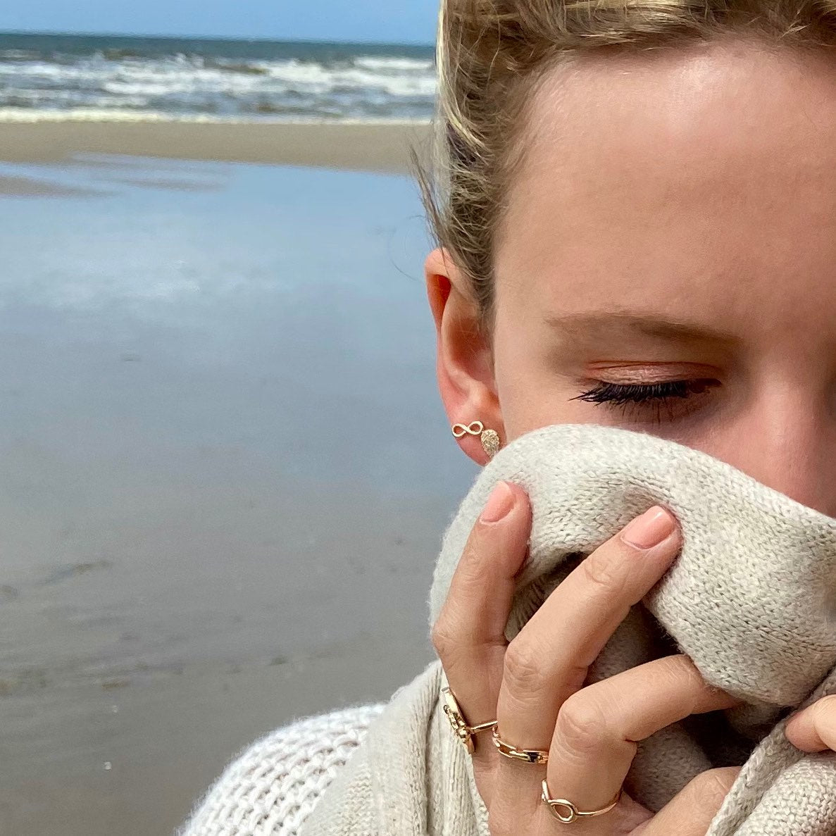 jeune femme blonde portant des boucles d'oreilles plaqué or Infini