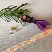 boucles d'oreilles puce lisse et plate en plaqué or posées sur une fleur de lavande