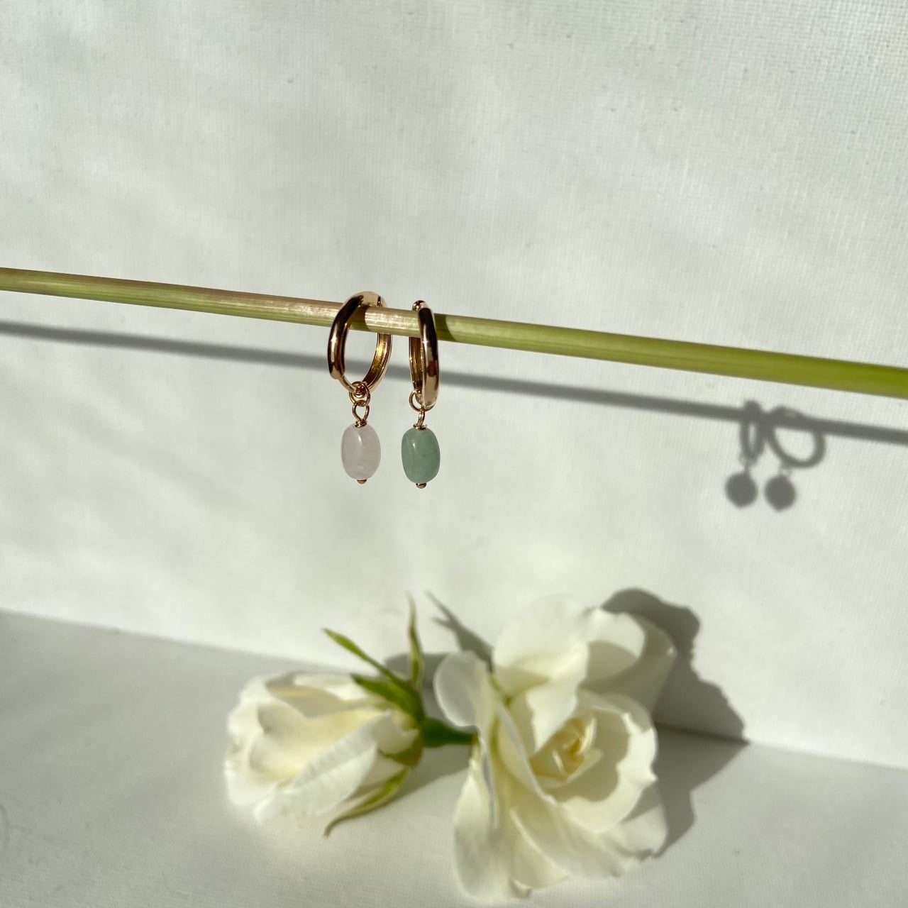 gros plan sur des petites créoles plaqué or agrémentées de perles rose et verte