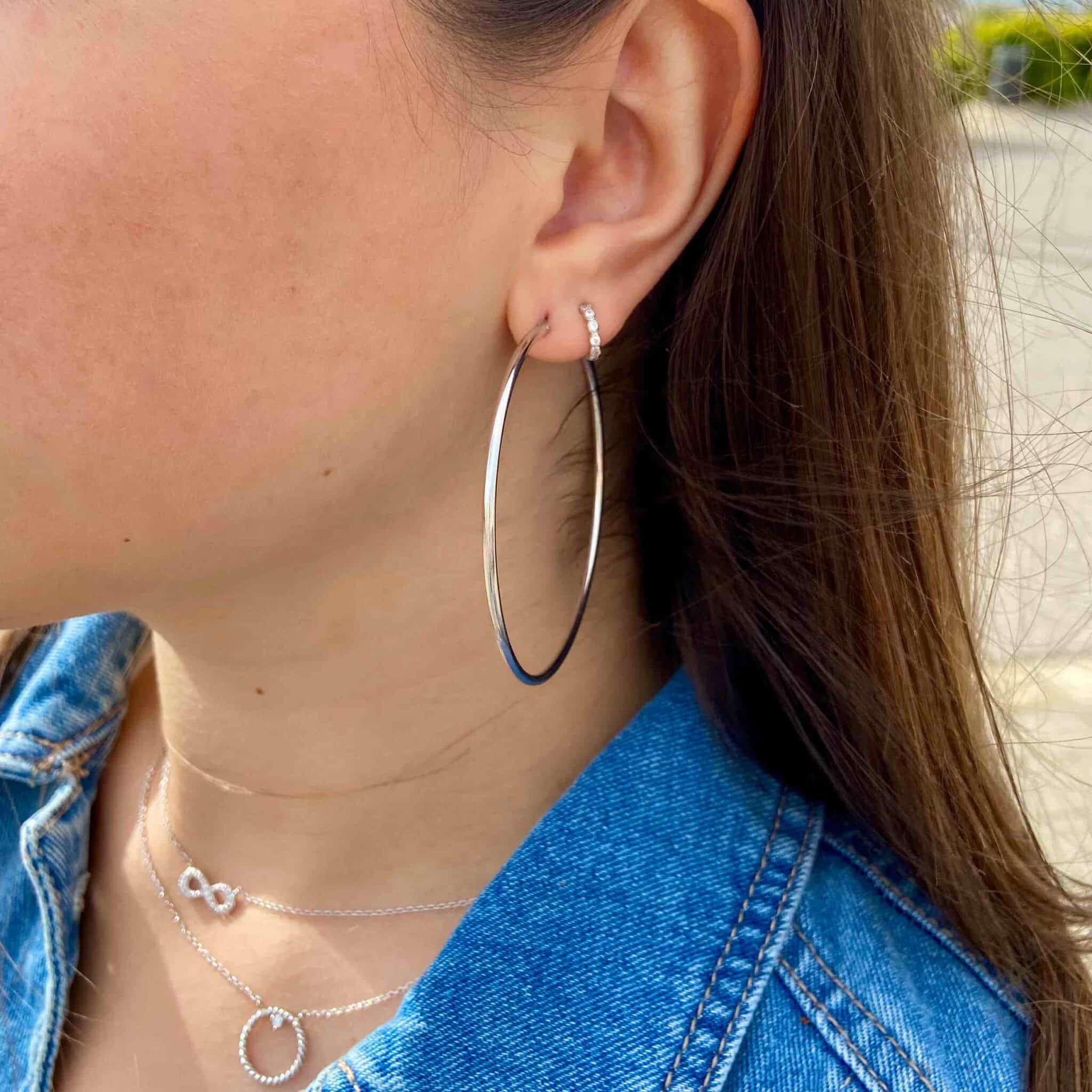 Boucles d'oreilles créoles argent portées par une jeune femme brune