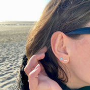 Boucles d'oreilles argent étoile plume portées par une jeune fille brune