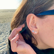 Boucles d'oreilles argent forme plume portées par une jeune fille brune