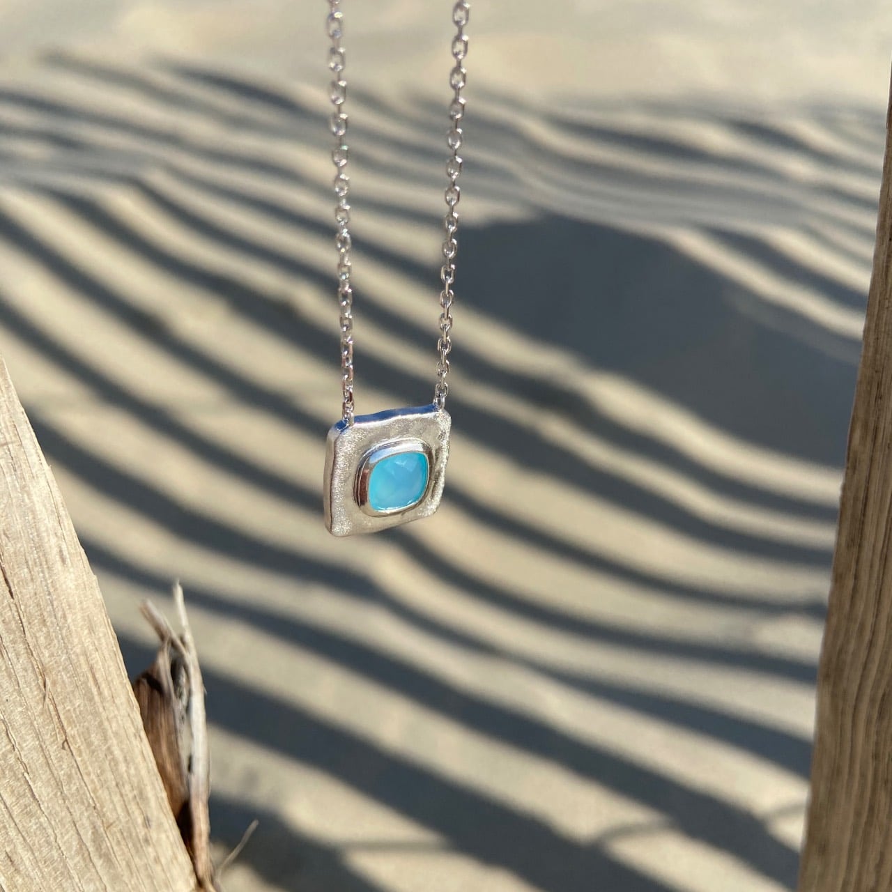 Collier argent pierre agate bleue sur fond plage