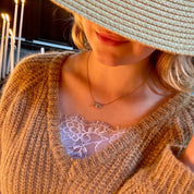 Collier plaqué or porté par une jeune femme au chapeau de paille