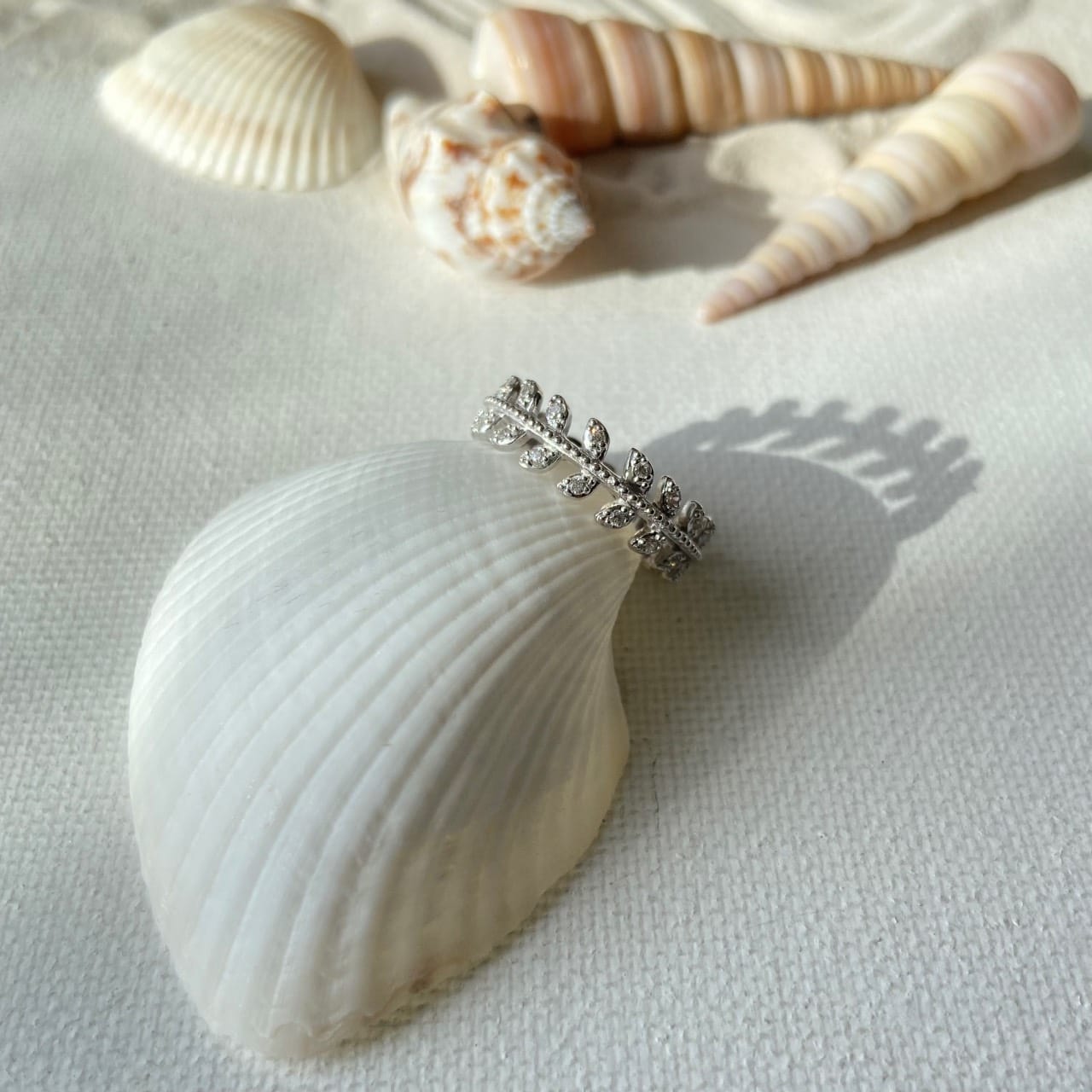 bague argent feuillage zirconium posée sur un coquillage