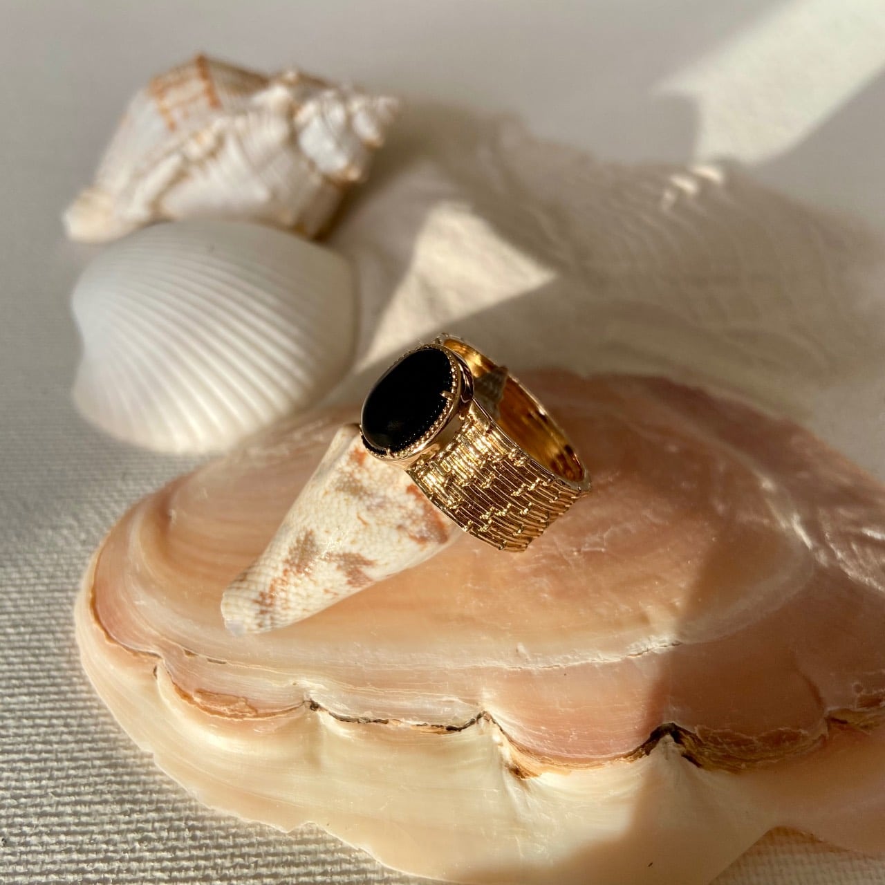 Bague plaqué or agate noire posée sur un coquillage