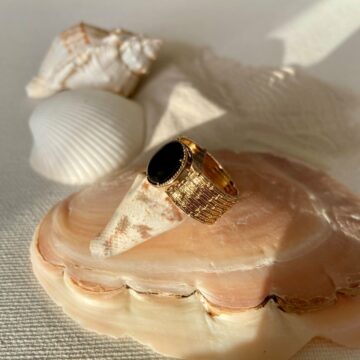 Bague plaqué or agate noire posée sur un coquillage