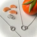 Boucles d'oreilles collier et bracelet avec deux sphères serties de zirconium présentés avec une mandarine