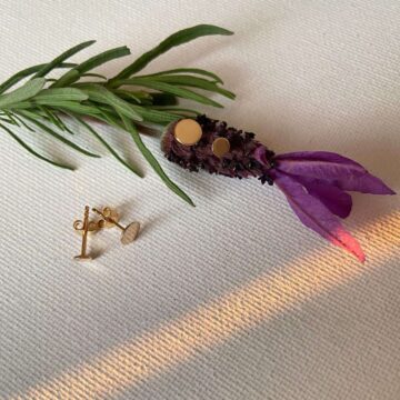 boucles d'oreilles puce lisse et plate en plaqué or posées sur une fleur de lavande