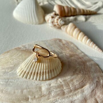 bague zircon mocile en plaqué or posée sur un coquillage
