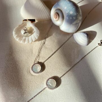 Collier bracelet et boucles en argent avec pastille nacre sur fond de sable et coquillage