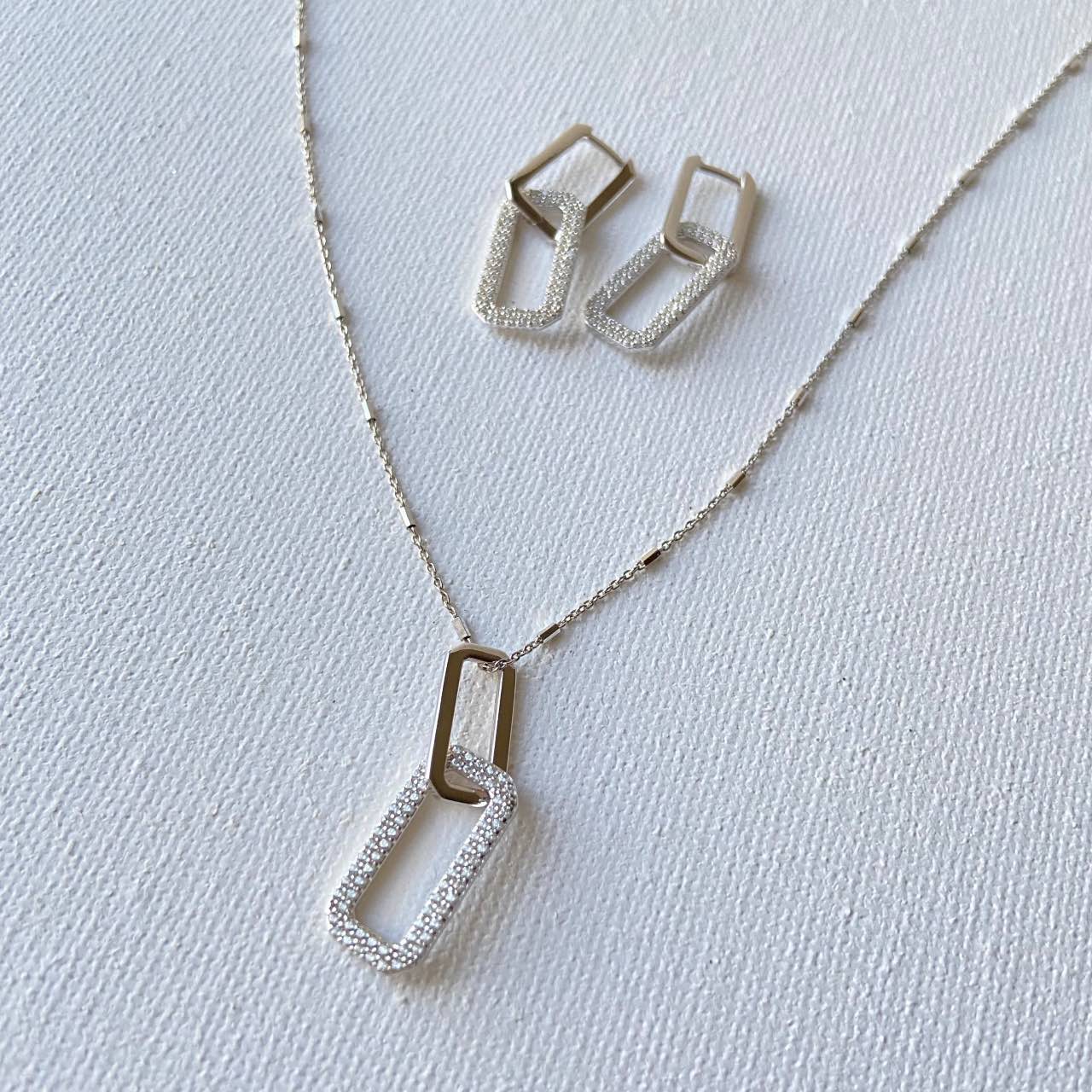 collier fantaisie argent, composé d'une chaîne pointillé et d'un pendentif avec deux beaux rectangulaires entrecroisés et multitude d'oxydes de zirconium