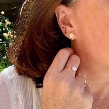 gros plan femme portant boucles d'oreilles Soleil avec zircons brillants